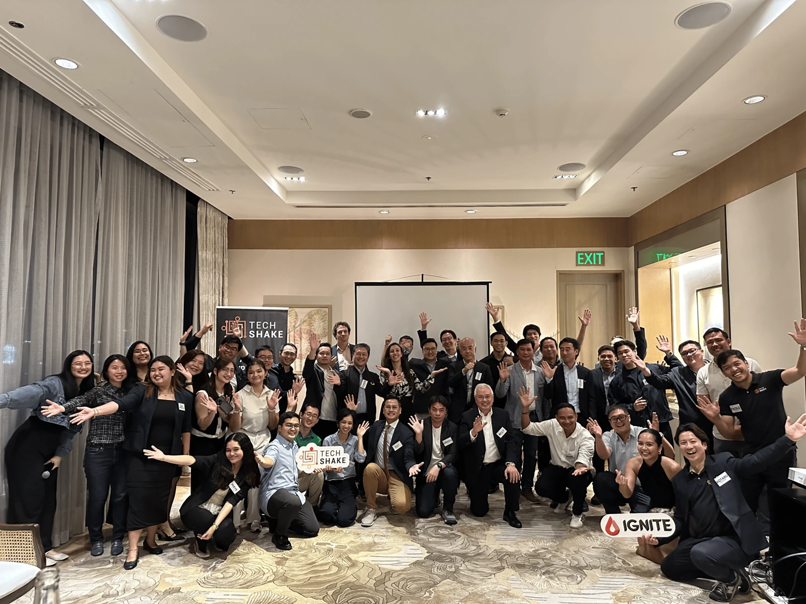 Founders and investors with hands raised at a TechShake Innovators' Dinner