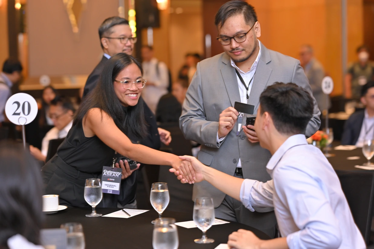 Attendees shaking hands across a table at IGNITE